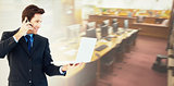 Composite image of businessman making a phone call while using a laptop