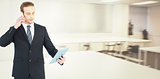 Composite image of serious businessman on the phone holding tablet