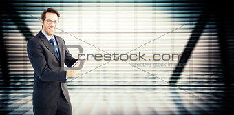 Composite image of businessman looking at the camera while using his tablet