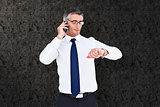 Composite image of businessman on the phone looking at his wrist watch