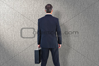 Composite image of businessman in suit holding a briefcase