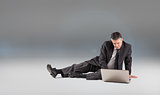 Composite image of mature businessman sitting using laptop