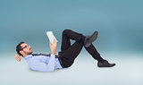 Composite image of businessman lying on the floor while reading a book