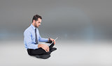 Composite image of cheerful businessman sitting on the floor using laptop