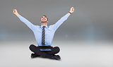 Composite image of businessman cheering with tablet sitting on floor