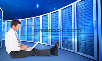 Composite image of businessman using laptop and smiling