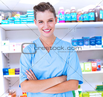Composite image of  smiling nurse in blue scrubs posing with arms crossed