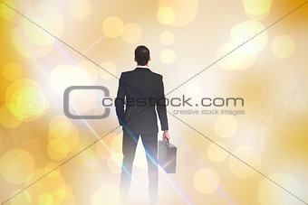 Composite image of rear view of businessman holding a briefcase