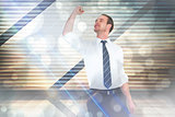 Composite image of businessman cheering with clenched fist