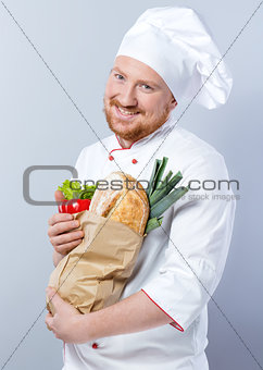 Head-cook smiling and holding package with fresh food
