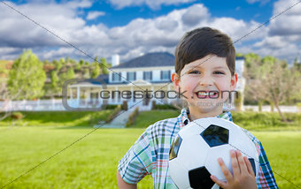 Smiling Young Boy Holding Soccer Ball In Front of House