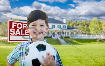 Boy Holding Ball In Front of House and Sale Sign
