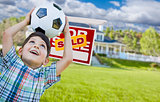 Boy Holding Ball In Front of House and Sold Sign