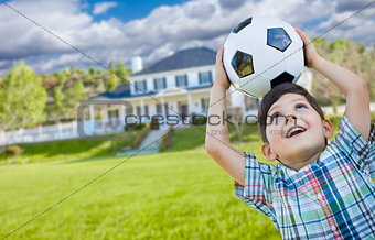 Smiling Young Boy Holding Soccer Ball In Front of House