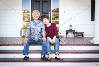 Senior Chinese Couple Sitting on Front Steps of Their House