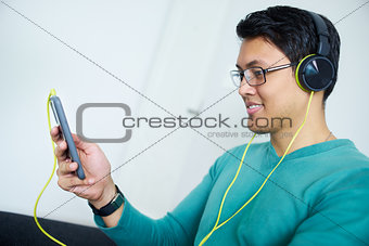 Chinese Man With Green Headphones Listens Podcast Phone At Home