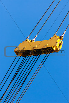 Large yellow pulley and cable assembly on blue sky.