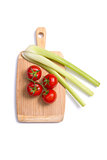 Fresh tomatoes and celery sticks on chopping board 