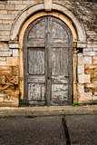 Old decaying wooden double doors in a stone archway