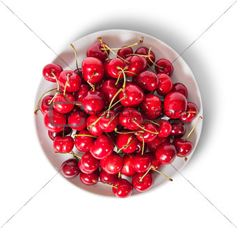 Red sweet cherries in white plate top view
