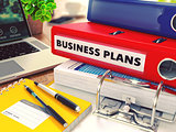 Business Plans on Red Office Folder. Toned Image.