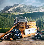 Fly fishing gear on wooden deck with lake 