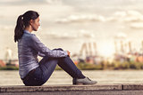 Thoughtful Woman Sits on Bench Facing at the River
