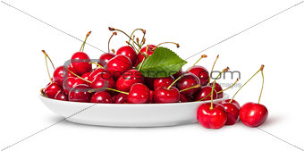 Sweet cherries with leaf on white plate and three near