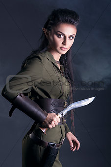 elf with a knife in his hand on a gray background