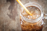 Glass of cola with ice on wooden table
