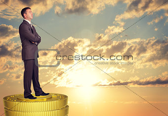 Thoughtful businessman standing on coins stack