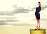 Happy businesswoman standing on coins stack 