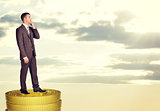 Thinking businessman standing on coins stack