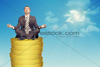 Businessmanin in lotus posture on coins stack