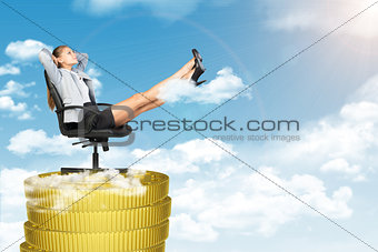 Businesswoman sitting in chair on coins stack
