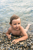 Three year boy bathes in the sea on pebbles