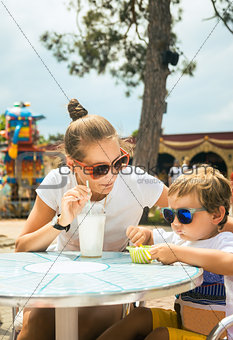 Young woman little son at the table in cafe in amusement park