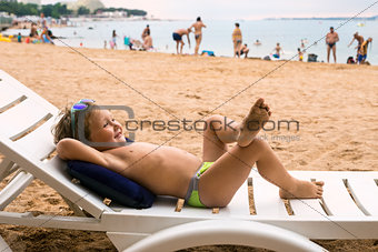Smiling baby sunning on deckchair on beach by sea