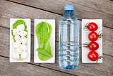 Tomatoes, mozzarella, green salad leaves and water bottle