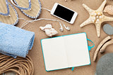 Smartphone and notepad on sea sand with starfish and shells