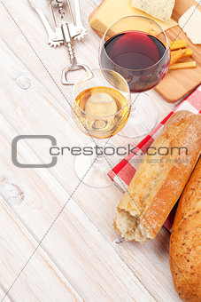 White and red wine, cheese and bread on white wooden table backg