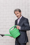 Mature businessman with watering pot