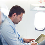 Businessman working with laptop on airplane.