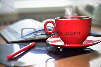 Red cup of coffee on the desk in the office