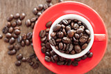 Red coffee cup with coffee beans on wooden table