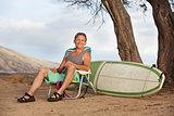 Smiling Man Sitting with Surfboard