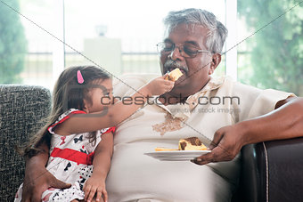 Granddaughter feeding grandfather cake