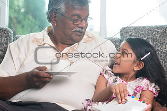 Granddaughter and grandfather reading book together