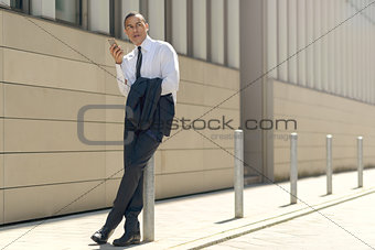 Businessman sitting on a bollard reading an sms