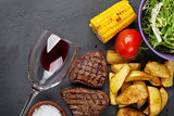 Beef steak with grilled potato, corn, salad and red wine
